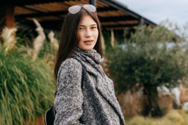 Koyu saçlı şık kız bir şehrin sokaklarında yürüyüş ve poz gri ceket, sokak stil ve moda