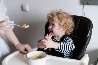 Annem onun küçük kıvırcık oğlu, aile akşam yemeği, çocuk gülüyor ve sevinir beslemeleri