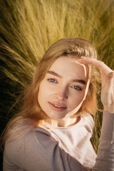 Schöne junge blonde Mädchen mit blauen Augen posiert draußen in der Sonne — Stockfoto