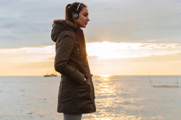 Motiverad ung flicka står vid havet i hörlurar, gatan utbildning och motivation — Stockfoto