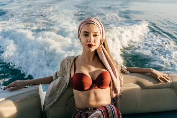 En lyxig ung flicka i en vacker baddräkt simmar på hennes stora vita yacht på det blå havet, har resten — Stockfoto