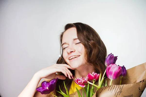 Glückliche attraktive junge Frau hält einen großen Blumenstrauß in der Hand, feiert den Weltfrauentag und genießt den Frühling — Stockfoto