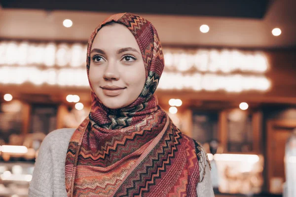 Hermosa chica árabe con pañuelo en la cabeza sentado en acogedora cafetería musulmana y sonriendo — Foto de Stock
