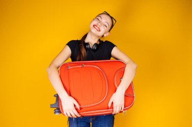 mutlu genç kadın tatile gider büyük bir kırmızı bavul tutar