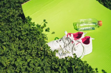 yeşil çim bir yoga mat ve spor spor ayakkabıları, sağlıklı bir yaşam tarzı yatıyor