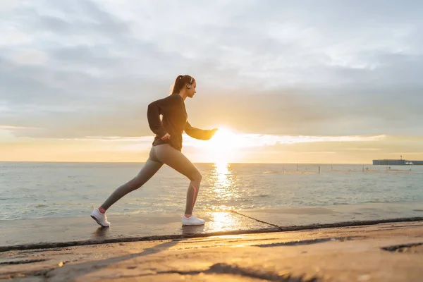 En inspirerad ung aktiv flicka körs vid havet i kvällssolen, strålar vill vara smal och vacker — Stockfoto