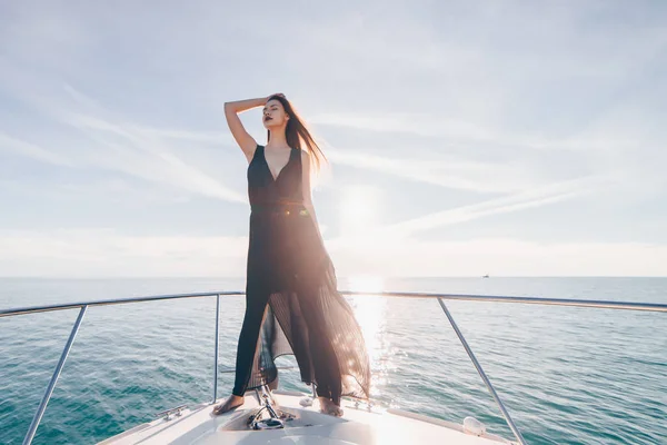 Una chica de pelo largo de lujo está de pie en un gran yate blanco, disfrutando de viaje por el mar —  Fotos de Stock