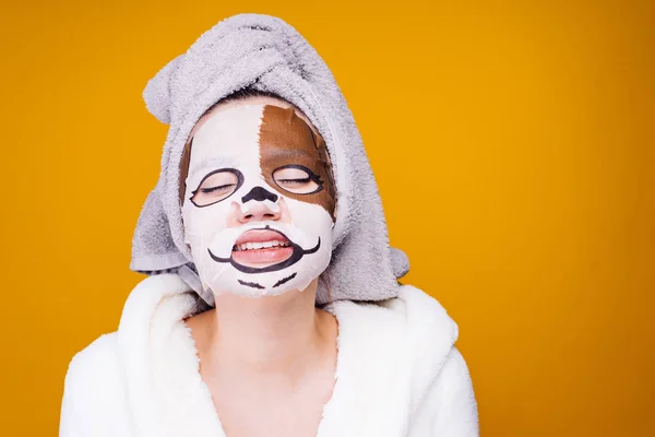 Divertida joven con una toalla en la cabeza mostrando la lengua, en la mascarilla con bozal de animal — Foto de Stock