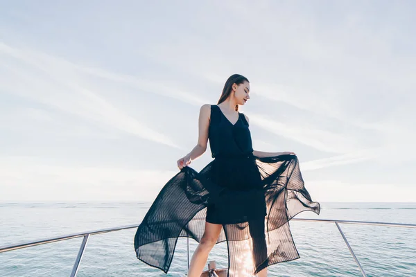 An attractive young girl in a black dress is standing on her white yacht, sailing to the Caribbean islands — Stock Photo, Image