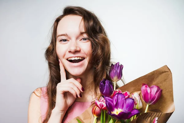 Eine lachende junge Frau genießt den Frühling, hält einen großen Strauß duftender Blumen in der Hand, feiert den Muttertag — Stockfoto