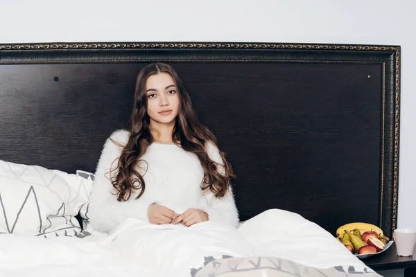 Krásné dlouhé vlasy dívka sedí v posteli brzy ráno, užívat denně mimo — Stock fotografie