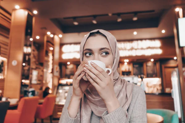 Gyönyörű Arab lány hidzsáb italok illatos kávét a café — Stock Fotó