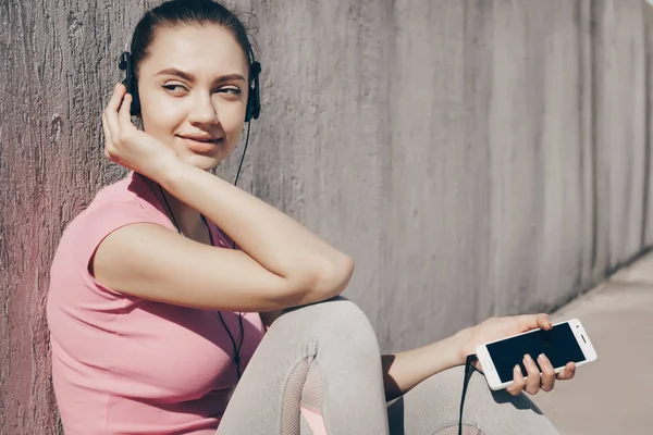 Krásné sportovní dívka poslechu hudby ve sluchátkách, odpočívá po náročném tréninku venku — Stock fotografie