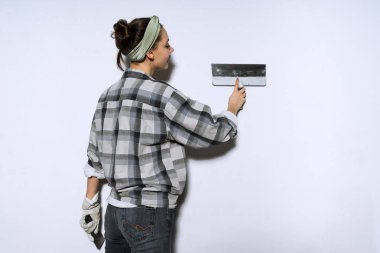 genç kız bir spatula ile duvarlar tesviye daire, onarım işi ekose gömlekli