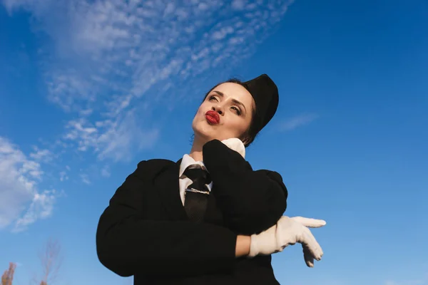 Νεαρή όμορφη γυναίκα αεροσυνοδός σε ομοιόμορφο στέκεται κάτω από το γαλάζιο του ουρανού και σκέφτεται σε αεροπλάνα — Φωτογραφία Αρχείου