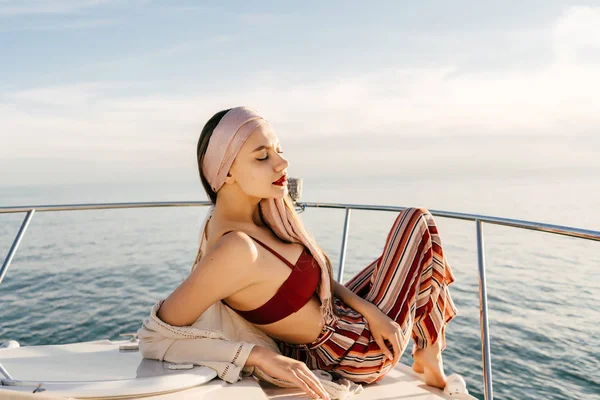 A luxurious rich woman lies on her white yacht in the rays of the evening sun and sails to the Caribbean islands — Stock Photo, Image