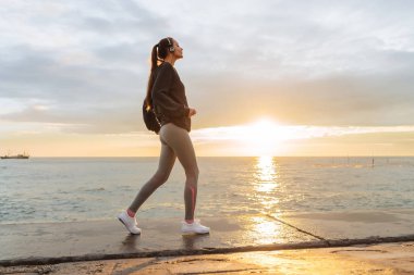 aktif genç kız, denizde kulaklıklar, yanındaki bir maraton için hazırlanıyor çalışıyor