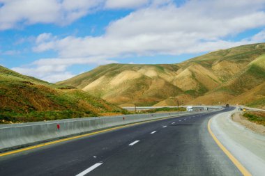 yol, Otoyol, Dağlık yeşil yamaçları ve mavi gökyüzü altında tepelerin eteklerinde