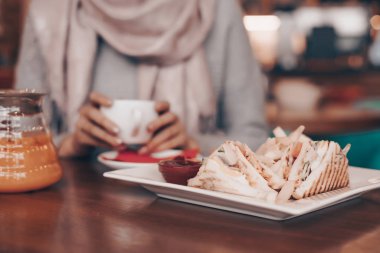 genç bir kız rahat bir kafede oturuyor, hoş kokulu kahve içecekler ve lezzetli bir yemek yiyor