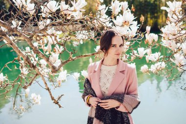 güzel genç kız pembe ceket parkta bahar güneşli bir günde yürür.