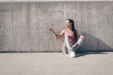ince genç kız yerde açık havada uzun bir egzersiz yaptıktan sonra oturur, sağlıklı bir yaşam tarzı olur, başparmak ortaya