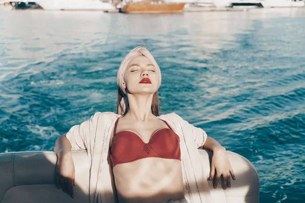 Uma menina atraente de luxo navega em seu iate branco junto ao mar, desfruta do resto e do sol — Fotografia de Stock