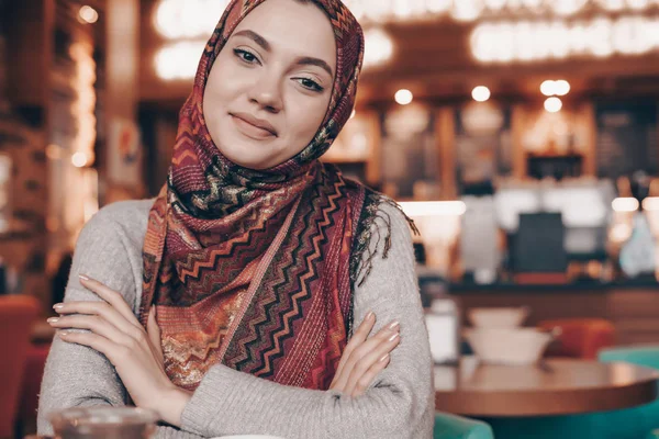 Hermosa joven árabe en hijab se sienta en acogedora cafetería y sonrisas — Foto de Stock