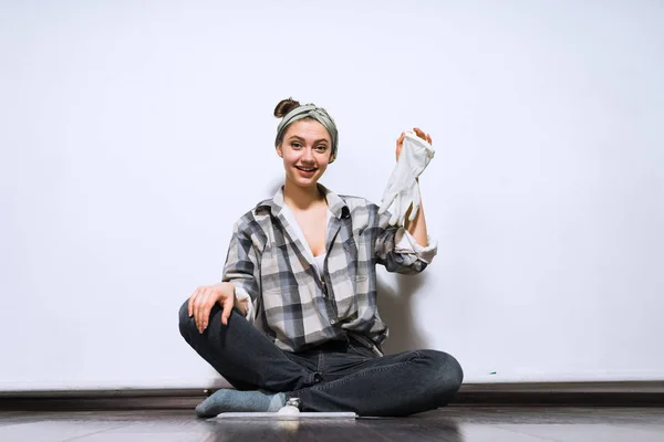 Lachende jong meisje zittend op de vloer, verwijderd rubberen handschoenen, reparatie — Stockfoto