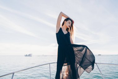 siyah elbiseli seksi genç kız onun yatta duruyor, gözleri kapalı, dinlenme zevk