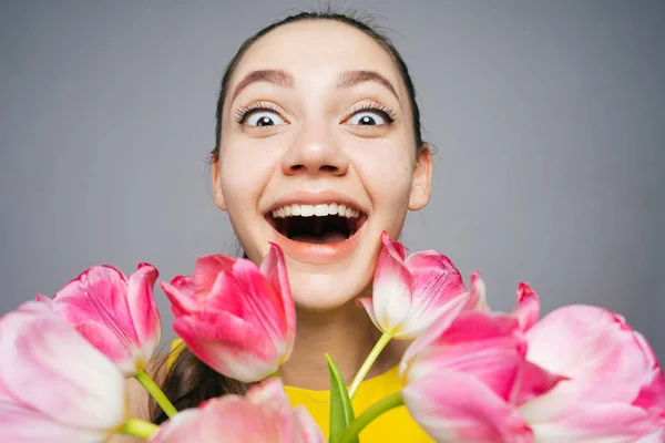 Смешная счастливая молодая девушка улыбается, держа большой букет ароматных цветов, отмечая День матери — стоковое фото