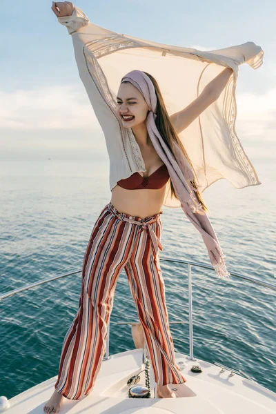 Stylish young girl laughs, stands on her white yacht against the blue sea, rich life — Stock Photo, Image