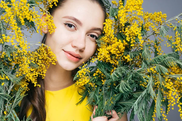 Belle jeune fille jouit d'un mimosa jaune parfumé et sourit — Photo