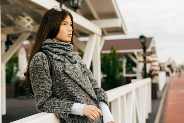 Fille de la ville aux cheveux foncés dans un manteau gris à la mode profitant du temps, marchant à l'extérieur, style de rue — Photo