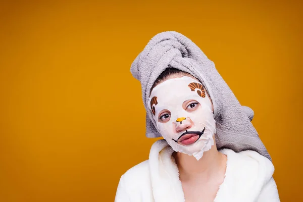 Roztomilá mladá dívka s ručníkem na hlavě vypadá po sobě, na její tváři vtipné masky s psí tvář — Stock fotografie