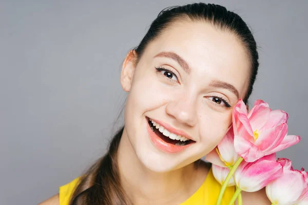 Gülüyor ve kokulu Pembe çiçek tutan sarı elbiseli mutlu gülümseyen kız — Stok fotoğraf