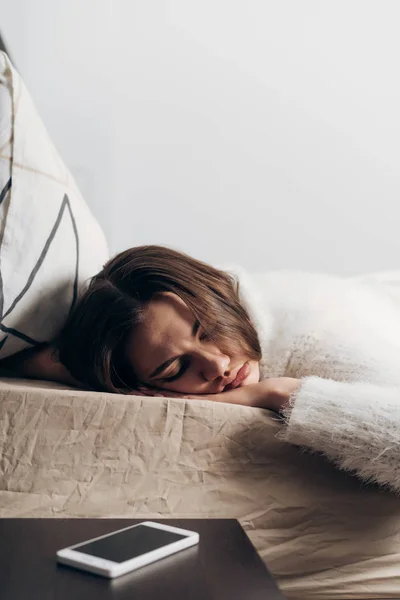 Ung flicka sover på sängen tidigt på morgonen, höra inte väckarklockan — Stockfoto