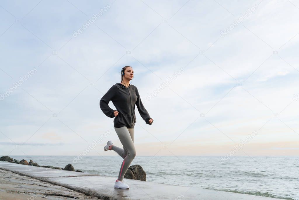 athletic young girl goes in for sports, runs along the waterfront outdoors, prepare for a marathon