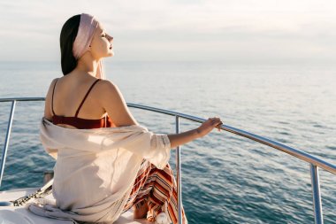 huzurlu bir genç kadın onun beyaz yelkenli üzerinde oturur, bir tatil ve güneş sahiptir