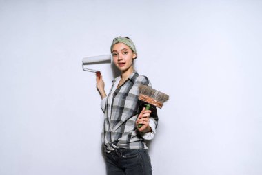 holding eller fırça ve silindir duvarları boyama için sevimli kız oluşturucu onarım daire, işi ekose gömlekli