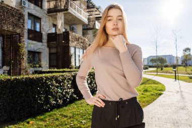 Kendine güvenen şık kız sarışın model açık havada güneş altında poz