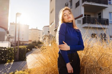 Mavi kazak açık havada güneş altında poz içinde kendine güvenen genç sarışın kız