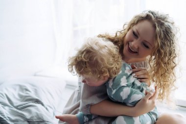 Dostu mutlu aile, kıvırcık genç anne küçük oğlu ile oynarken birlikte eğleniyor