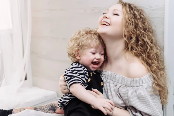 Happy friendly family, a young curly mother holding her little son in her arms, laughing and playing — Stock Photo, Image