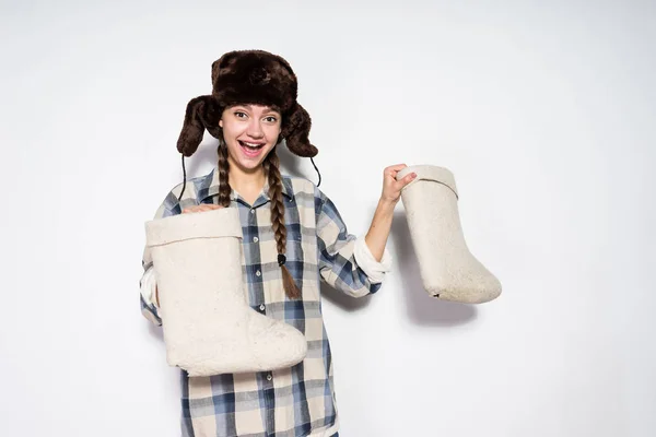 Feliz joven rusa chica en piel cálido sombrero feliz invierno, sosteniendo botas de fieltro gris en las manos — Foto de Stock