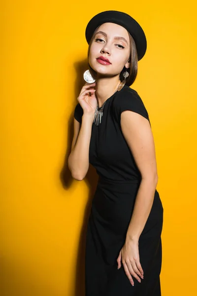 검은 드레스에 오렌지 배경에 포즈 유행 모자 고급 스러운 자신감 어린 소녀 모델 — 스톡 사진