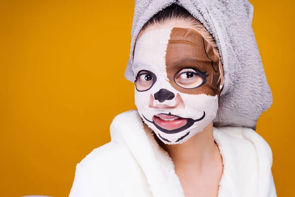 Funny young girl with a towel on her head after shower, face mask with muzzle of a dog, smiling — Stock Photo, Image