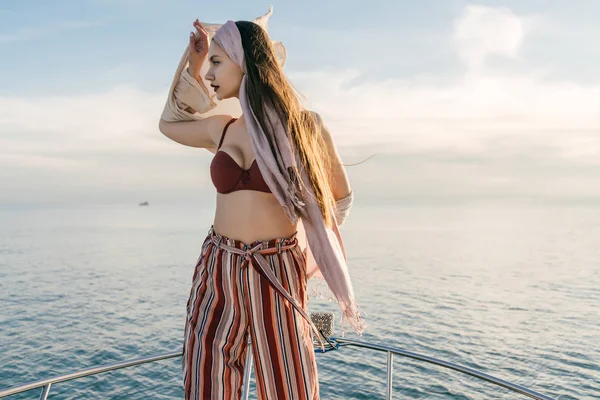 Stylish long-haired girl is standing on her white yacht in the sun, sailing to the Caribbean islands on vacation — Stock Photo, Image