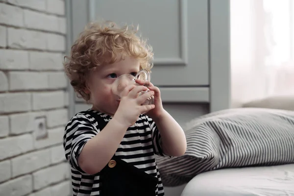 Söta lockigt barn pojke dricksvatten från mugg — Stockfoto