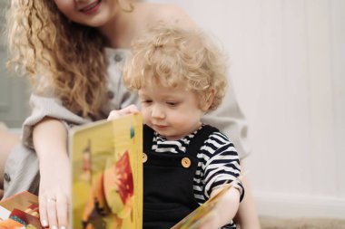 neşeli dostu aile, genç bir anne geçirdiği zaman küçük kıvırcık oğlu ile okuma öğretir