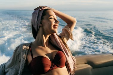 mutlu zengin kadın dinlenme sahiptir, deniz kenarında, gülümsüyor onun beyaz yatta yelken